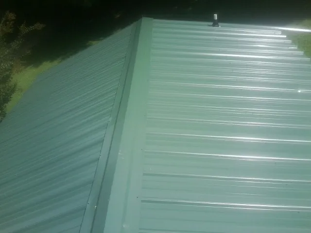 New green metal panels meeting at the ridge of a roof — Flat Roof Repair work by our crew in Mineral