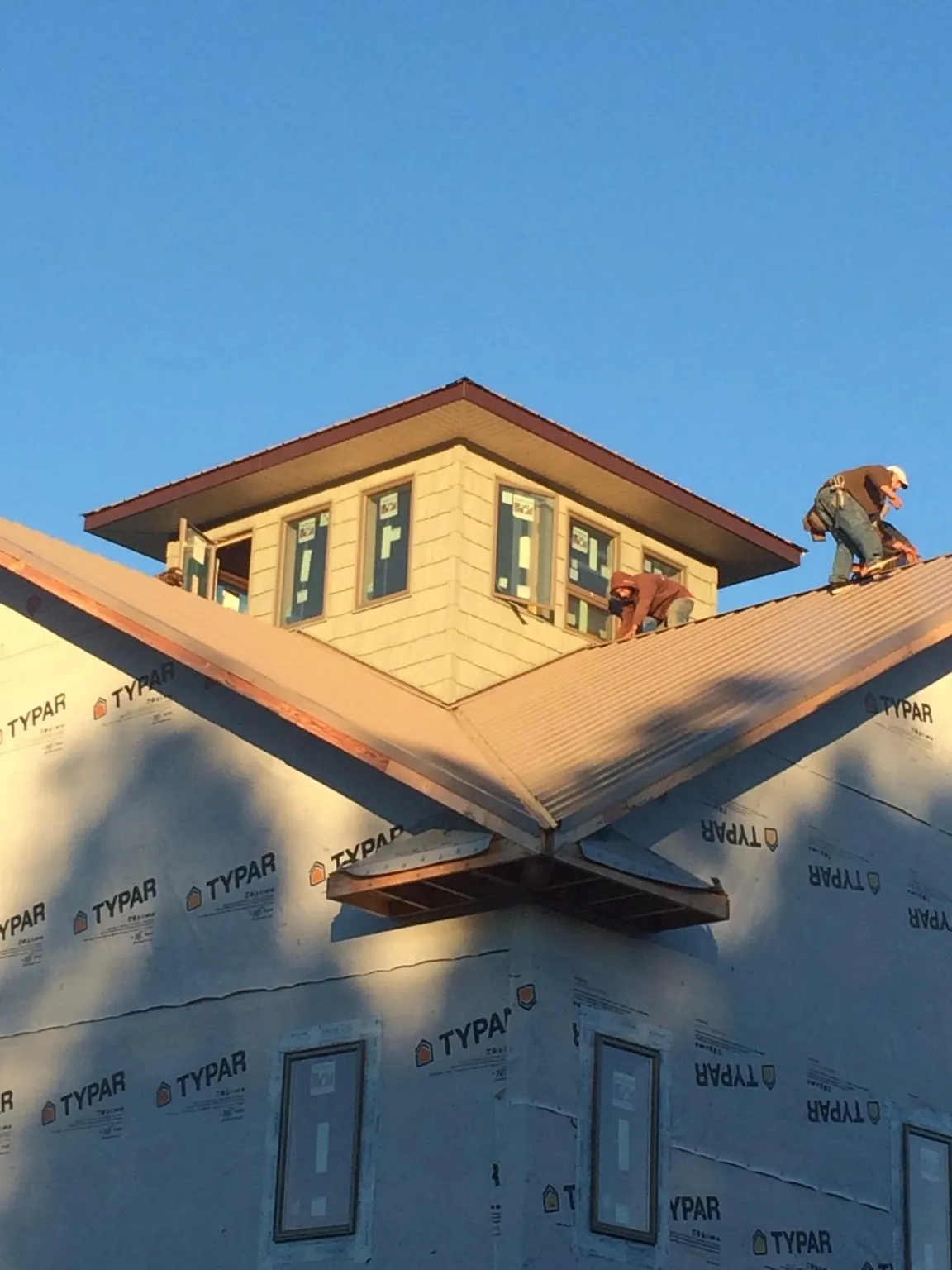 Roofers working around a rooftop cupola on a new metal roof at sunset — Roof Waterproofing in Mineral by Roofing Brothers